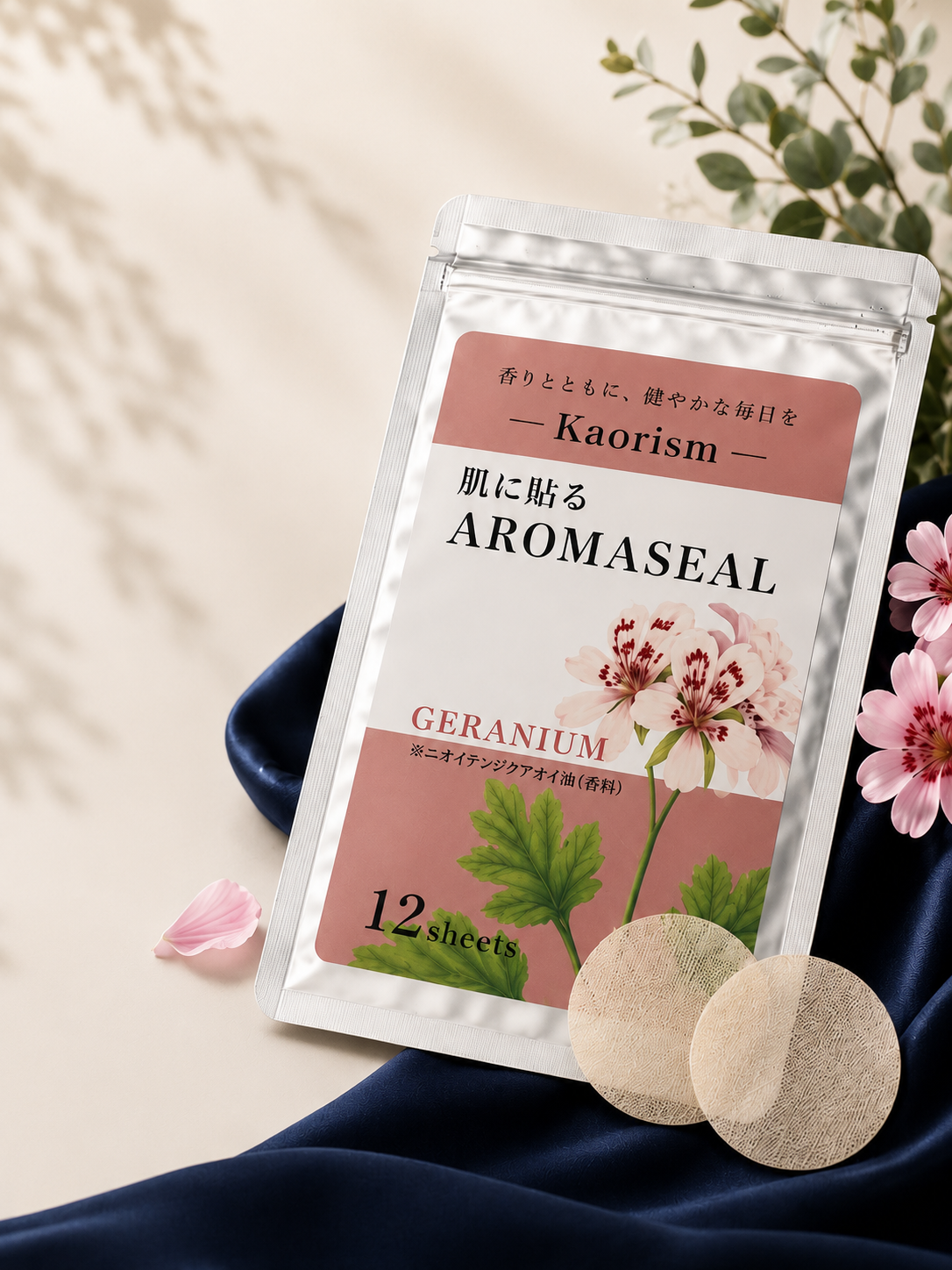 ネイビーのシルクの上に置かれた、肌に貼るAROMASEALのパッケージとゼラニウムの花